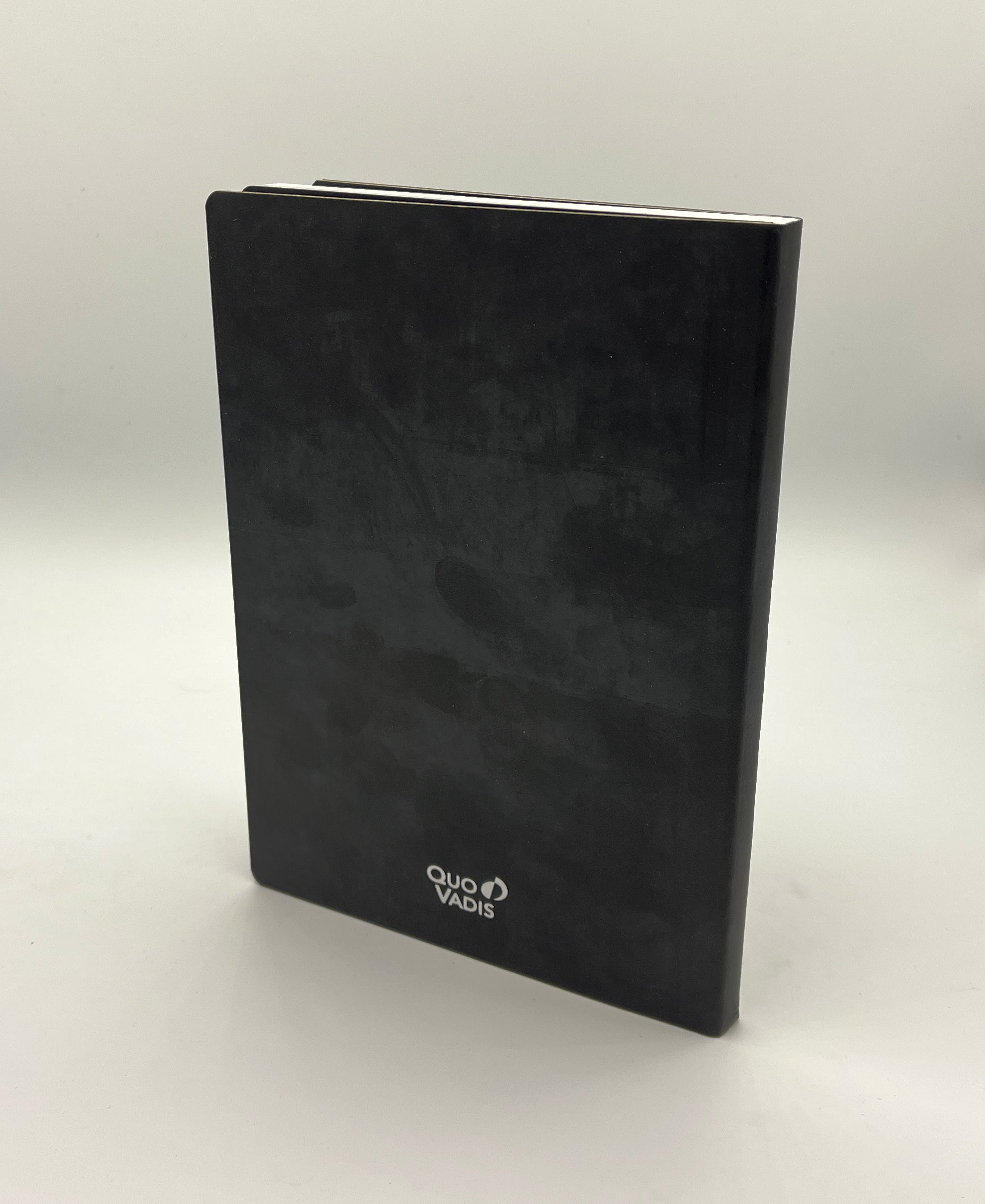 Black notebook with 'Quo Vadis' branding on a white background