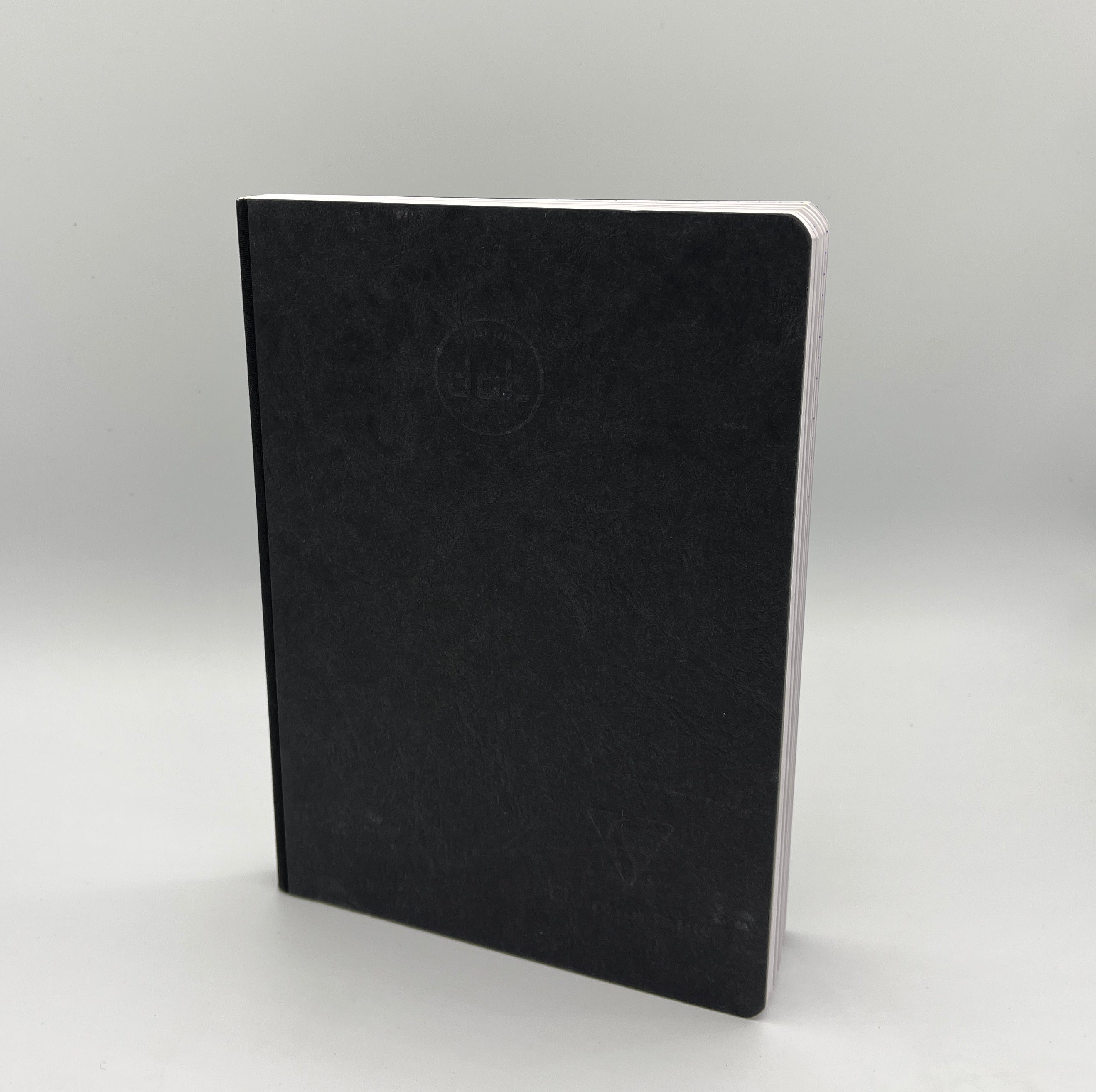 Black notebook with a visible brand logo on a light gray background