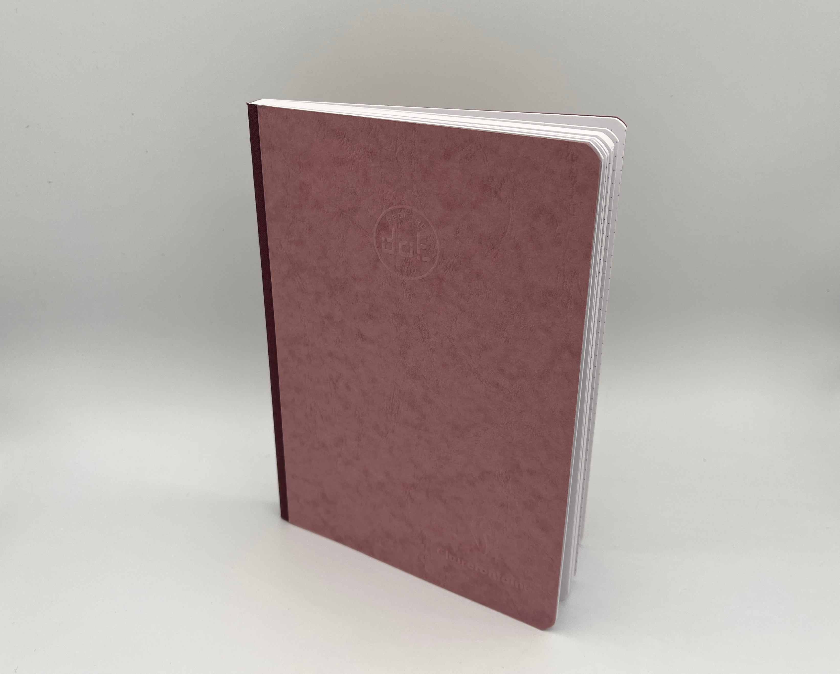 Maroon notebook with a logo on a light gray background